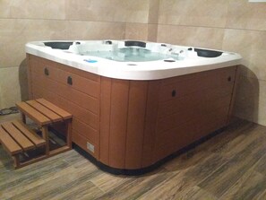 A hot tub with a wooden bench and a small step leading into it.