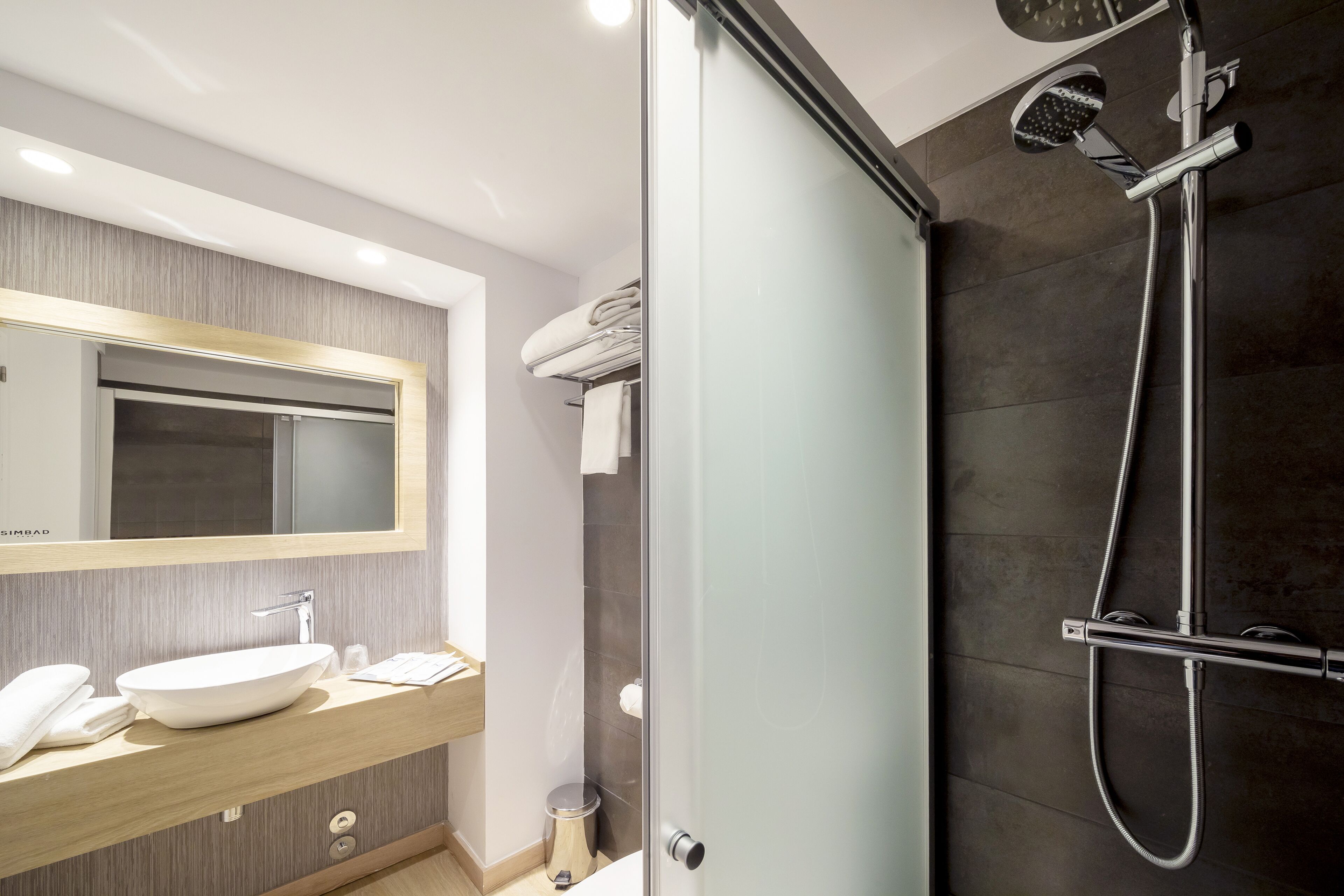 A modern bathroom with a large mirror, a sink, and a shower area.
