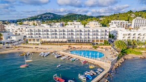 A coastal hotel with a swimming pool, multiple balconies, and a marina with boats. - Hotel Simbad (Ibiza Town)