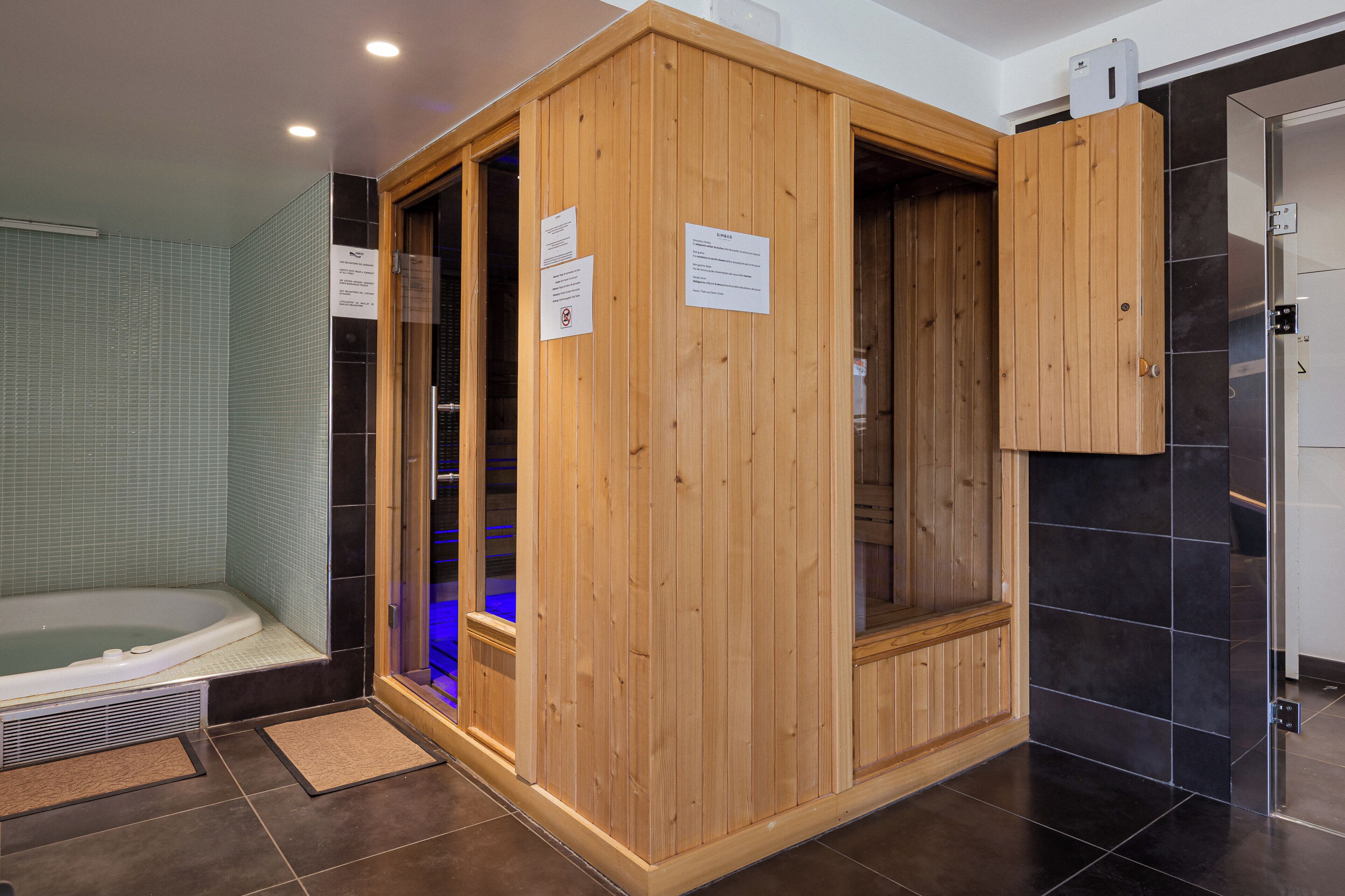 A sauna room with wooden walls, a tiled floor, and a visible door.