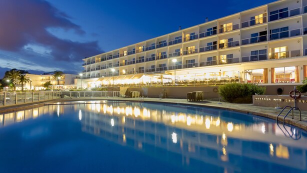 A hotel with a swimming pool, multiple balconies, and outdoor seating areas. - Hotel Simbad (Ibiza Town)