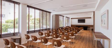 A conference room with rows of chairs, a TV screen, and large windows.