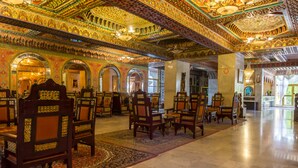 A spacious hall with ornate ceiling and arches, featuring rows of wooden chairs and tables. - Hotel Jugurtha Palace (Gafsa)