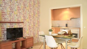 A modern kitchen with wooden cabinets, a stainless steel oven, and a dining area with a glass table and white chairs. - Apartamento Ulises Suite 1 (Málaga)