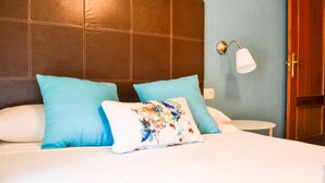 A hotel room with a large bed, two pillows, a nightstand, and a lamp. - Apartamento Ulises Suite 1 (Málaga)
