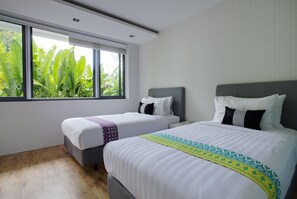 A hotel room with two beds, a large window with a view of greenery, and a tiled wall.