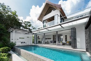 Una casa moderna con piscina, un espacio exterior cubierto y una estructura de dos pisos.
