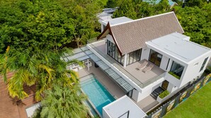 Vista aérea de una casa moderna con piscina, rodeada de exuberante vegetación.
