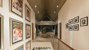 Un hall de hotel con carteles de películas enmarcados en las paredes, una escalera que conduce a un comedor y vistas al espacio del comedor.