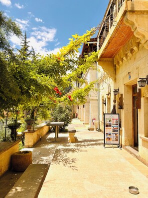 A narrow alleyway with a stone bench, potted plants, and a signboard. - Mozaik Otel (Avanos)
