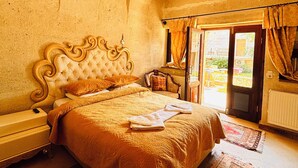 A bedroom with a large bed, a nightstand, a dresser, and a window with curtains. - Mozaik Otel (Avanos)