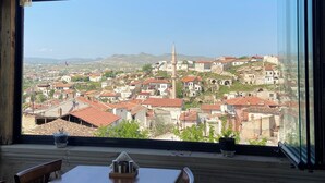 A room with a large window overlooking a historic town with red-roofed buildings and a prominent minaret. - Mozaik Otel (Avanos)