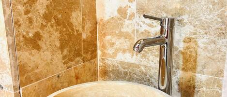 A bathroom with a marble sink and a modern faucet.