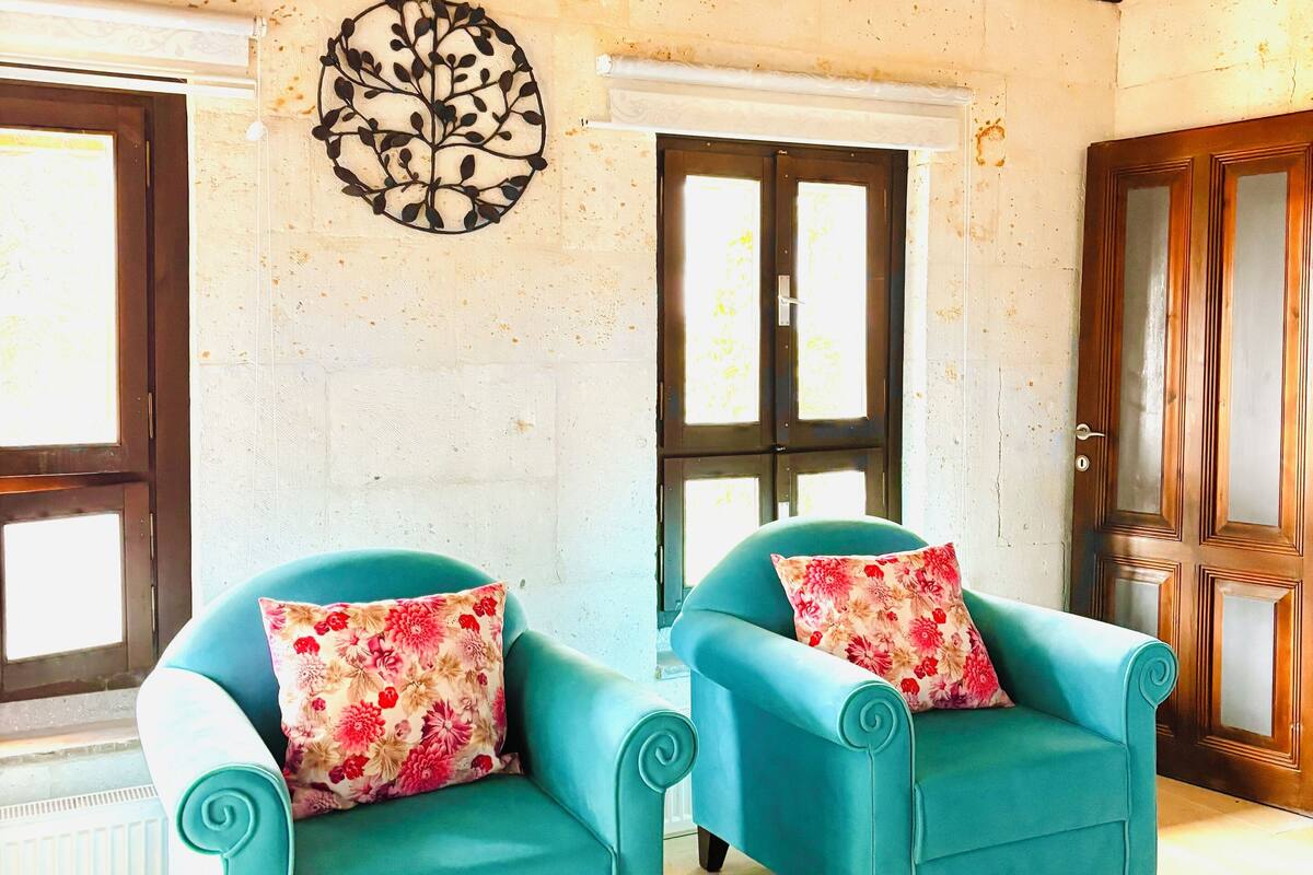 Una habitación con dos sillones turquesa, un adorno en la pared y techo de madera.