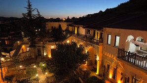 A hotel courtyard at dusk with stone architecture, a reception area, and outdoor seating. - Mozaik Otel (Avanos)