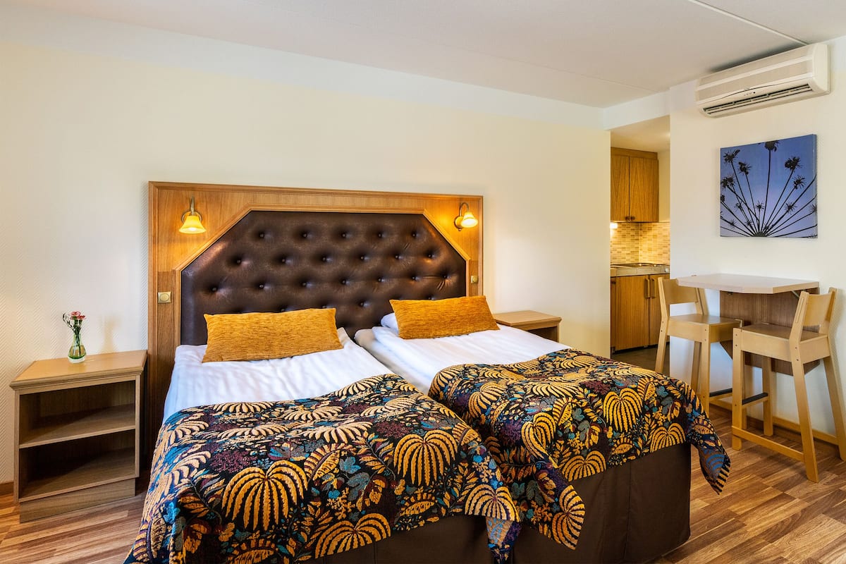 A double room with a large bed, two bedside tables, a desk, and a chair.
