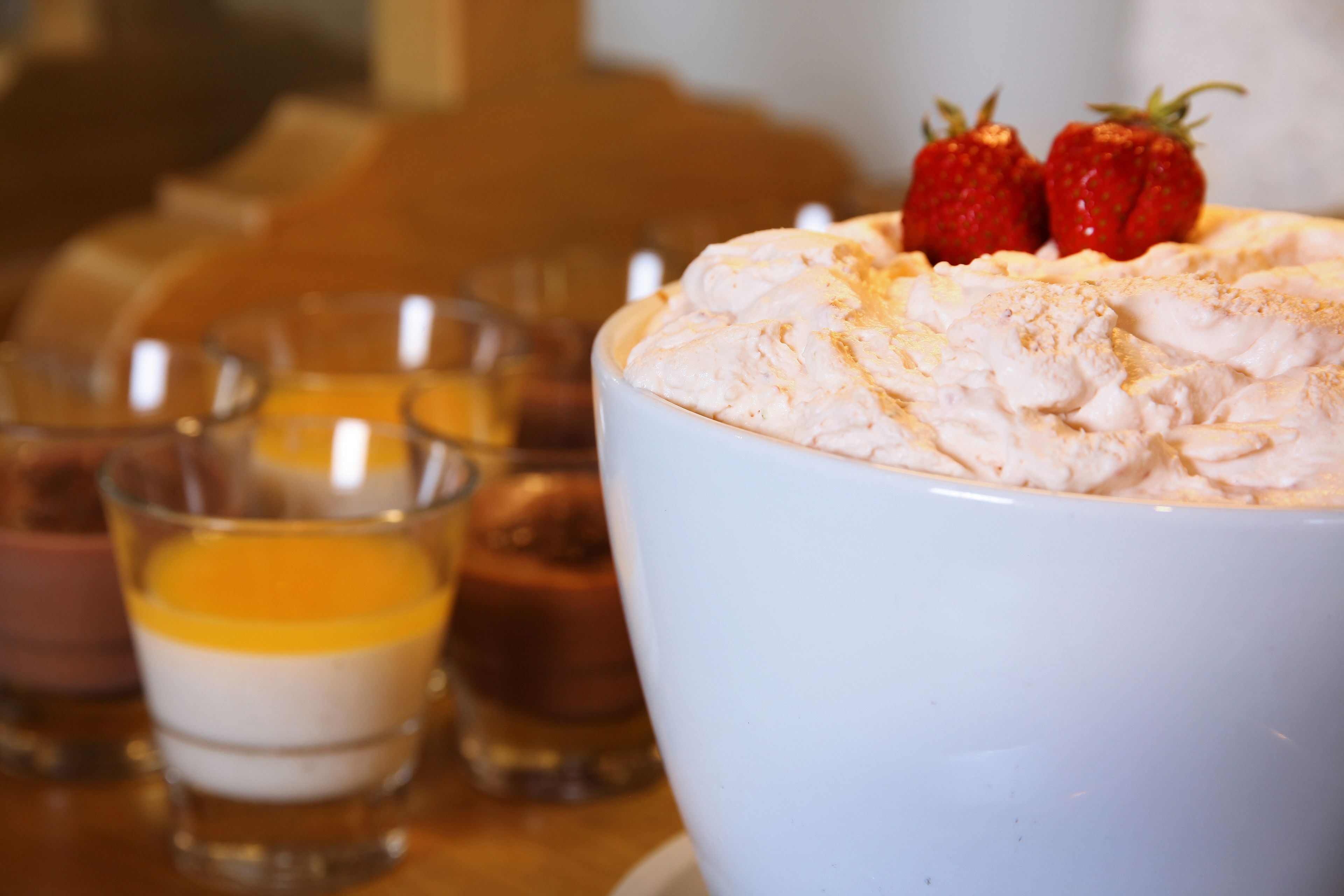 Een dessert met slagroom en aardbeien, geserveerd in een witte kom.
