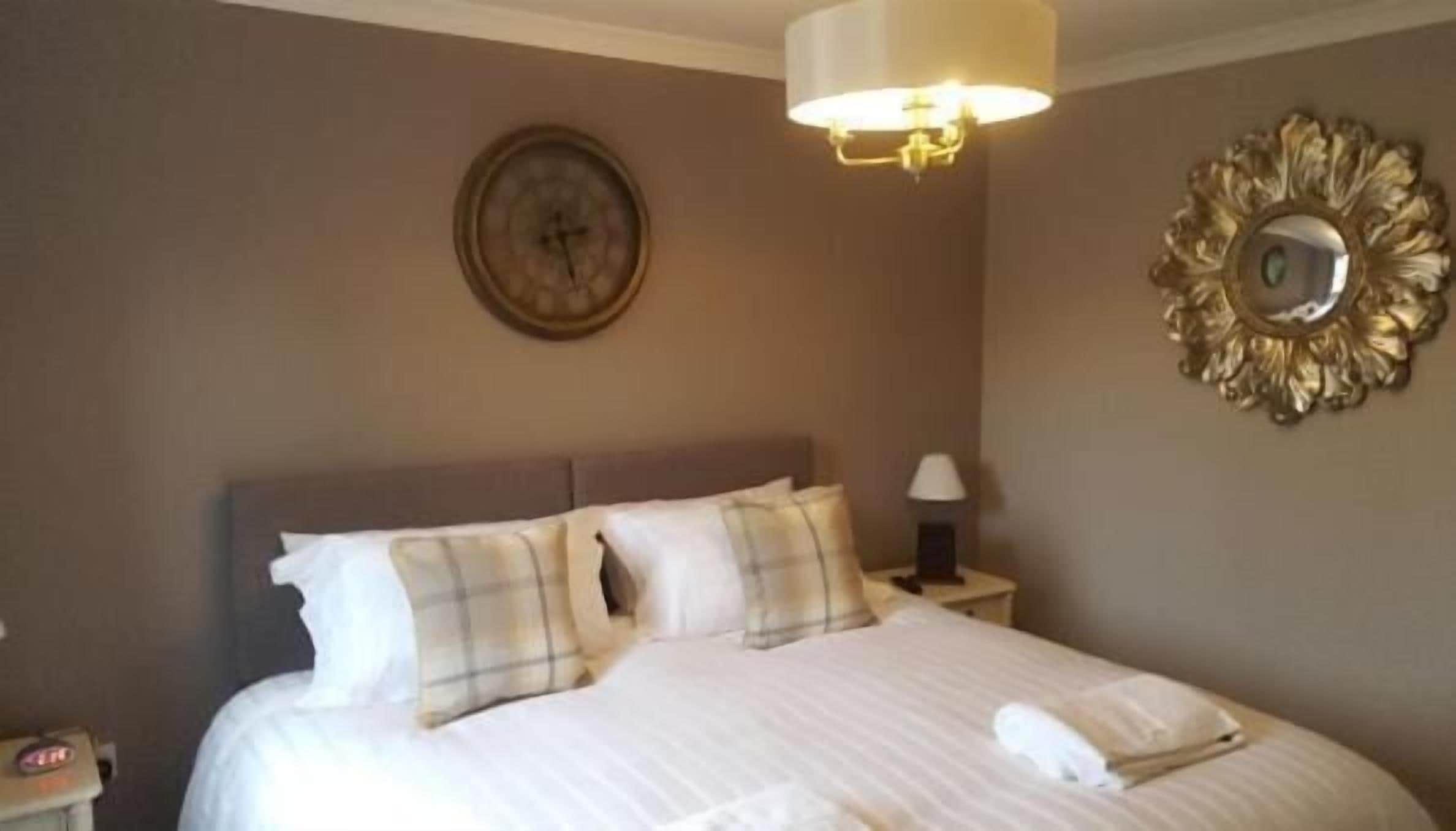 A neatly made bed with pillows and a bedside lamp in a hotel room.