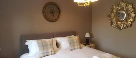A neatly made bed with pillows and a bedside lamp in a hotel room.