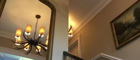 A staircase with white balusters and a chandelier with multiple light fixtures.