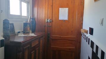 A wooden door with a sign, a checkered floor, and a window with blinds.