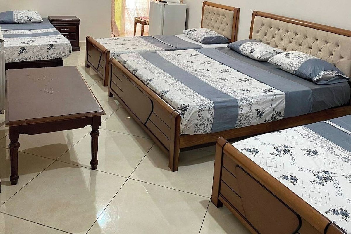 A hotel room with two beds, a desk, and a small table.