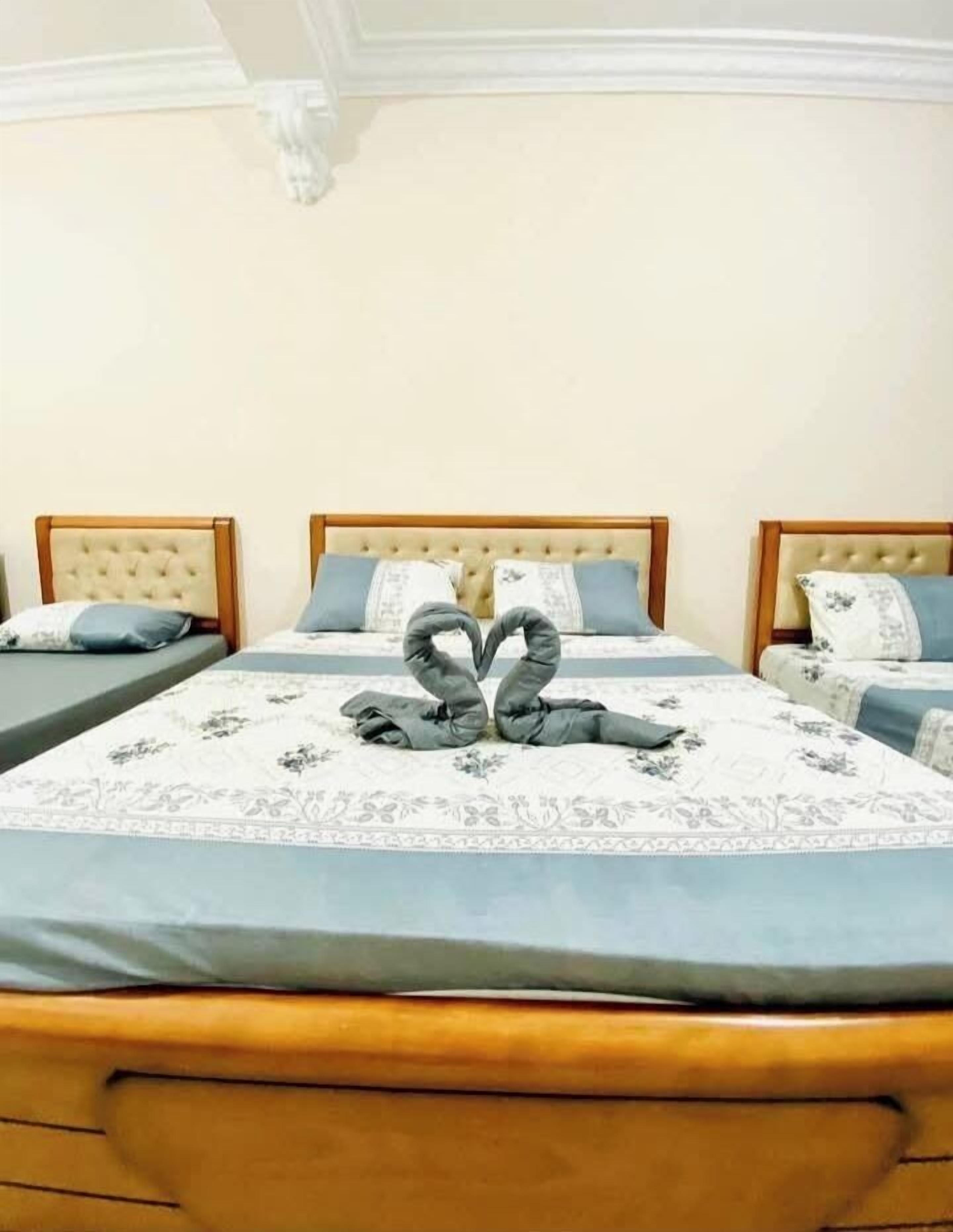 Una camera d'albergo con tre letti, ognuno con testiera e copripiumino a motivi floreali.