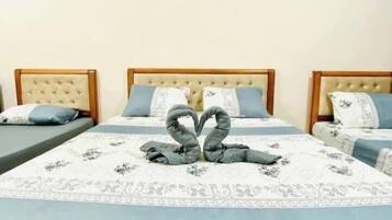 Habitación de hotel con tres camas, cada una con cabecera y colcha de estampado floral.