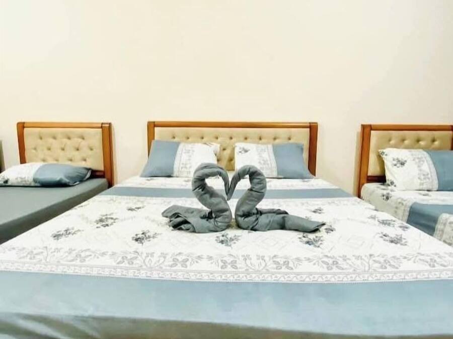 Habitación de hotel con tres camas, cada una con cabecera y colcha de estampado floral.