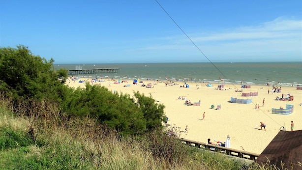A beach with a pier, sandy beach, and people. - The Corner House (Lowestoft)