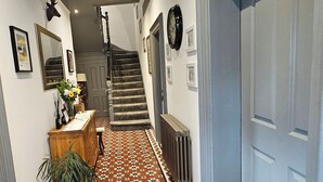 A hallway with patterned flooring, a staircase, and a door on the right. - The Corner House (Lowestoft)
