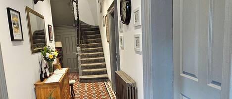 A hallway with patterned flooring, a staircase, and a door on the right.