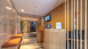 A reception area with a wooden desk, a computer, and a television on the wall.