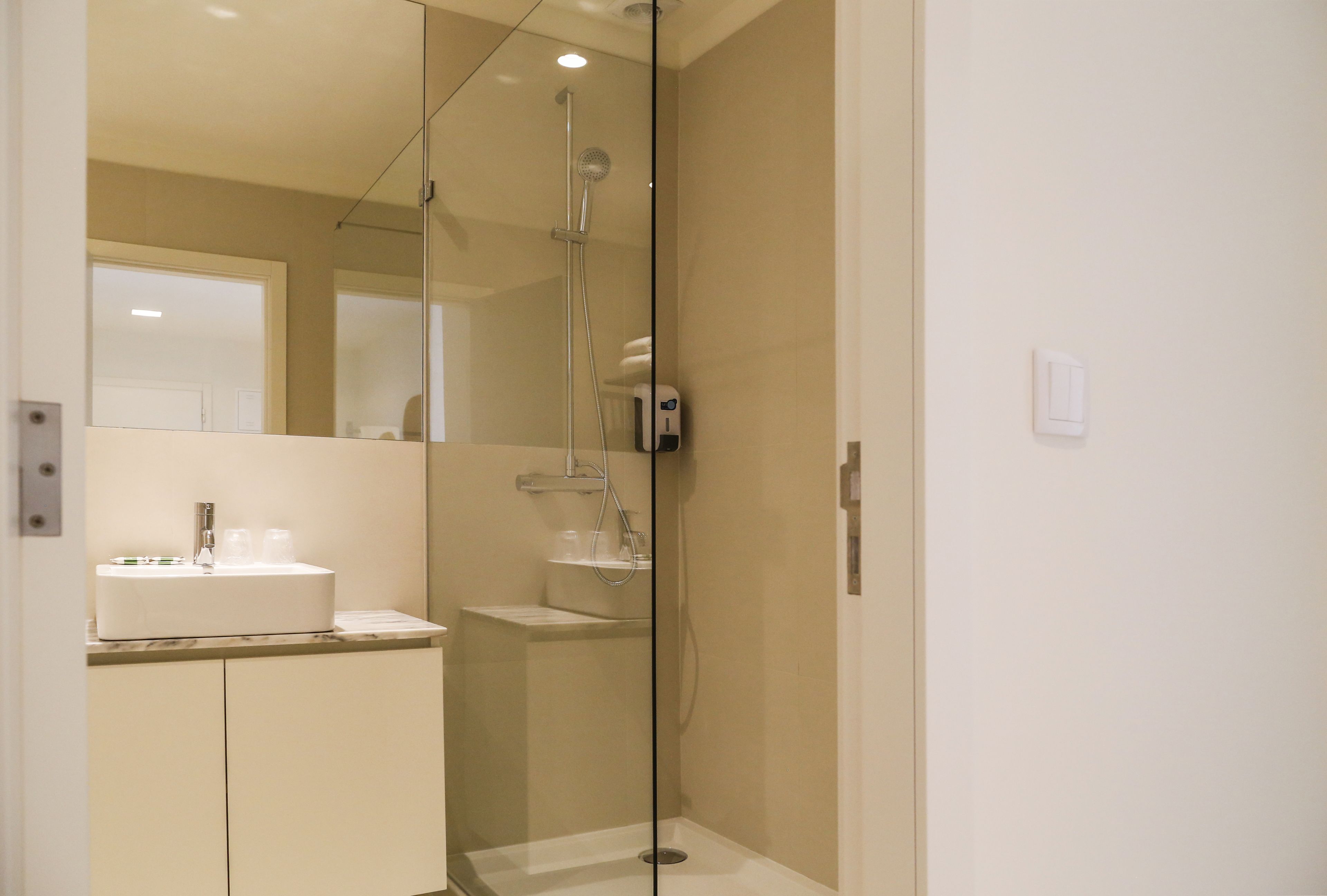 A modern bathroom with a glass-enclosed shower, a white sink, and a mirror.
