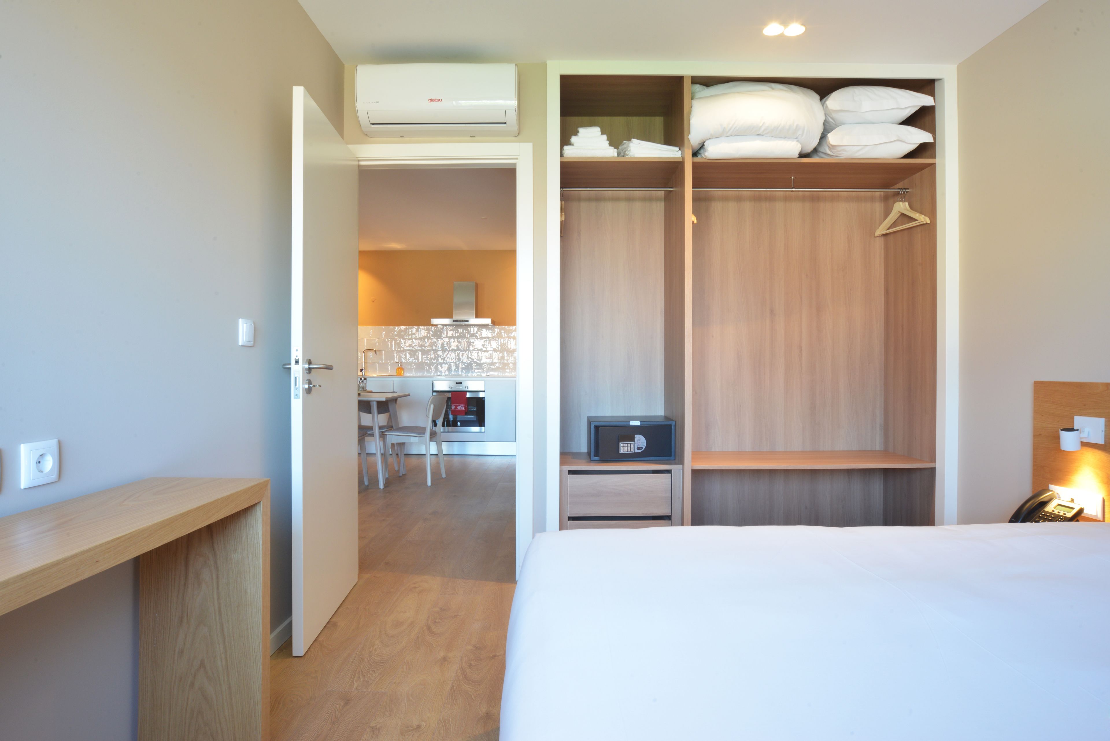 Una habitación de hotel con cama, escritorio, kitchenette y vestidor.