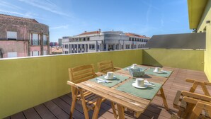 A wooden deck with a table set for dining, overlooking a cityscape.