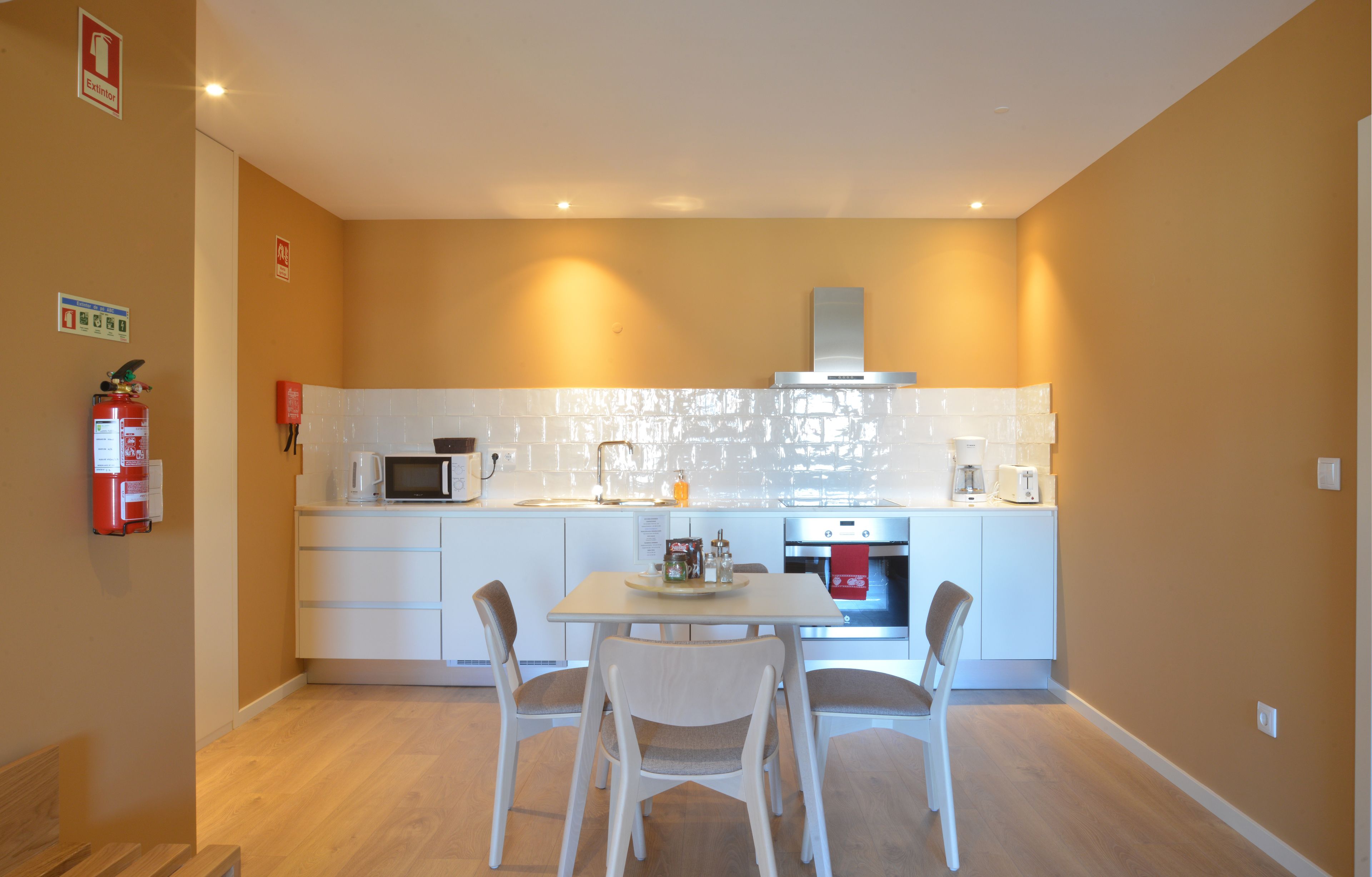 A compact kitchen with white cabinets, a microwave, a stove, and a dining table with chairs.