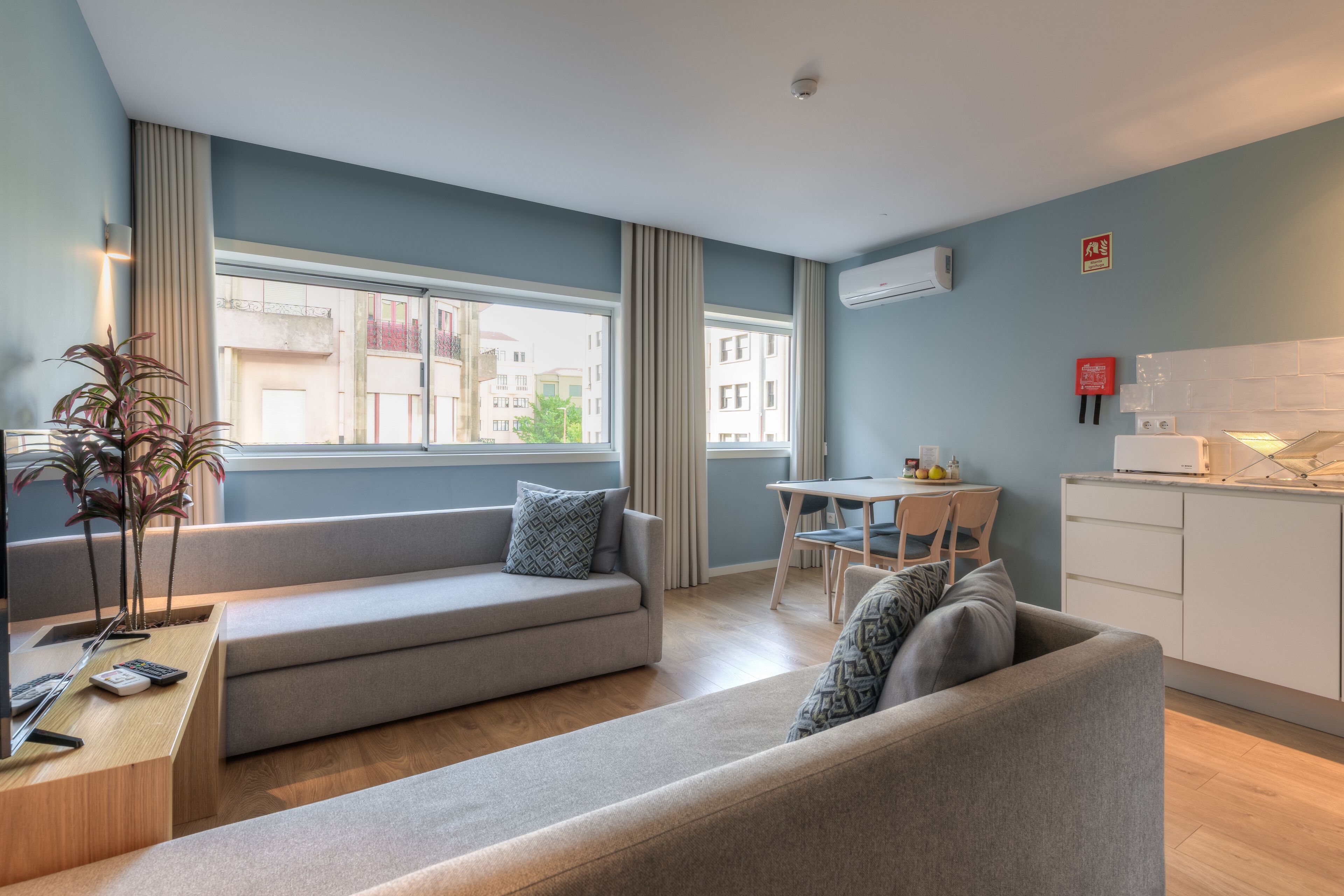 A modern living room with a sofa, a dining table, and a kitchen area.