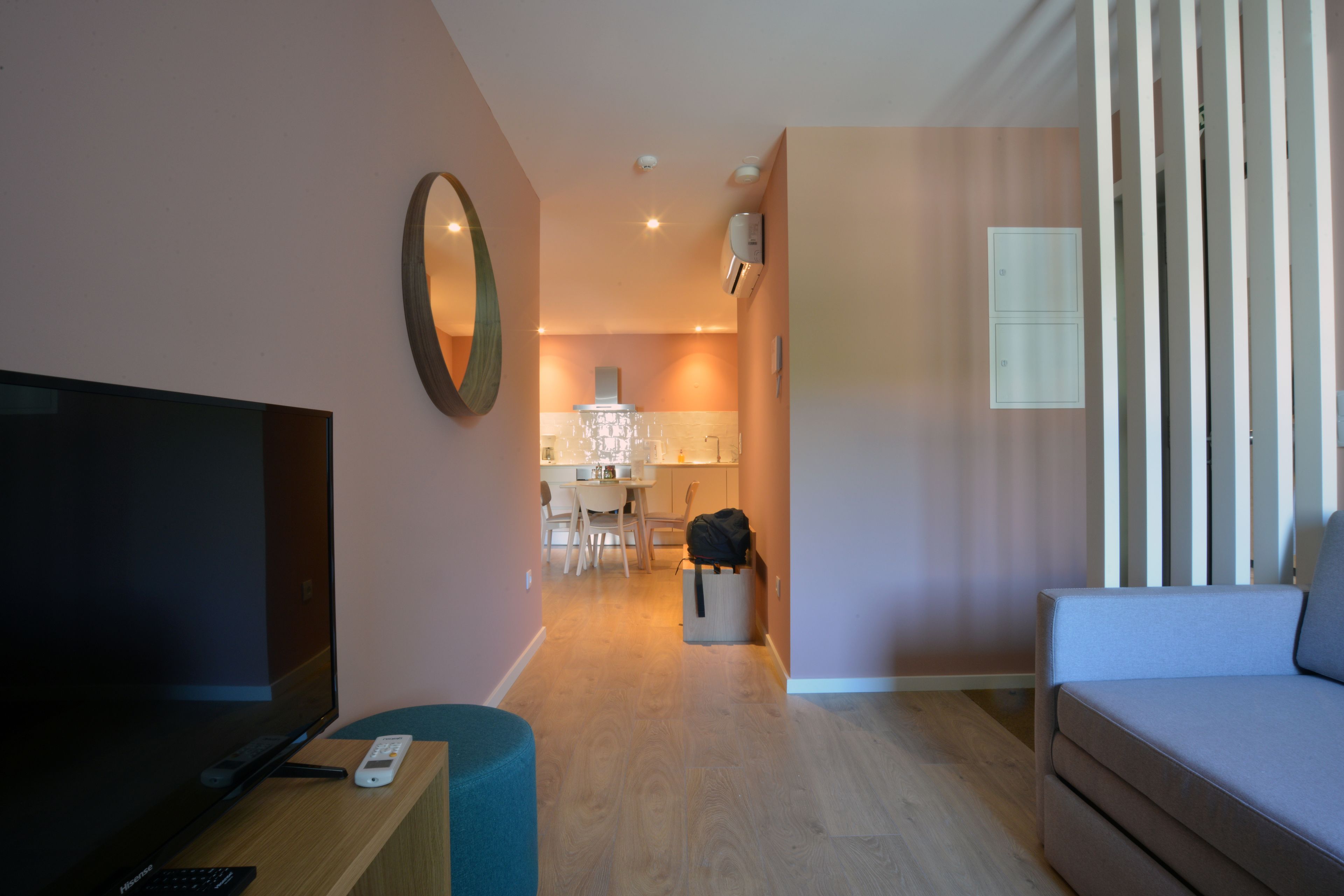 A modern living room with a flat-screen TV, a sofa, a coffee table, and a dining area with a table and chairs.