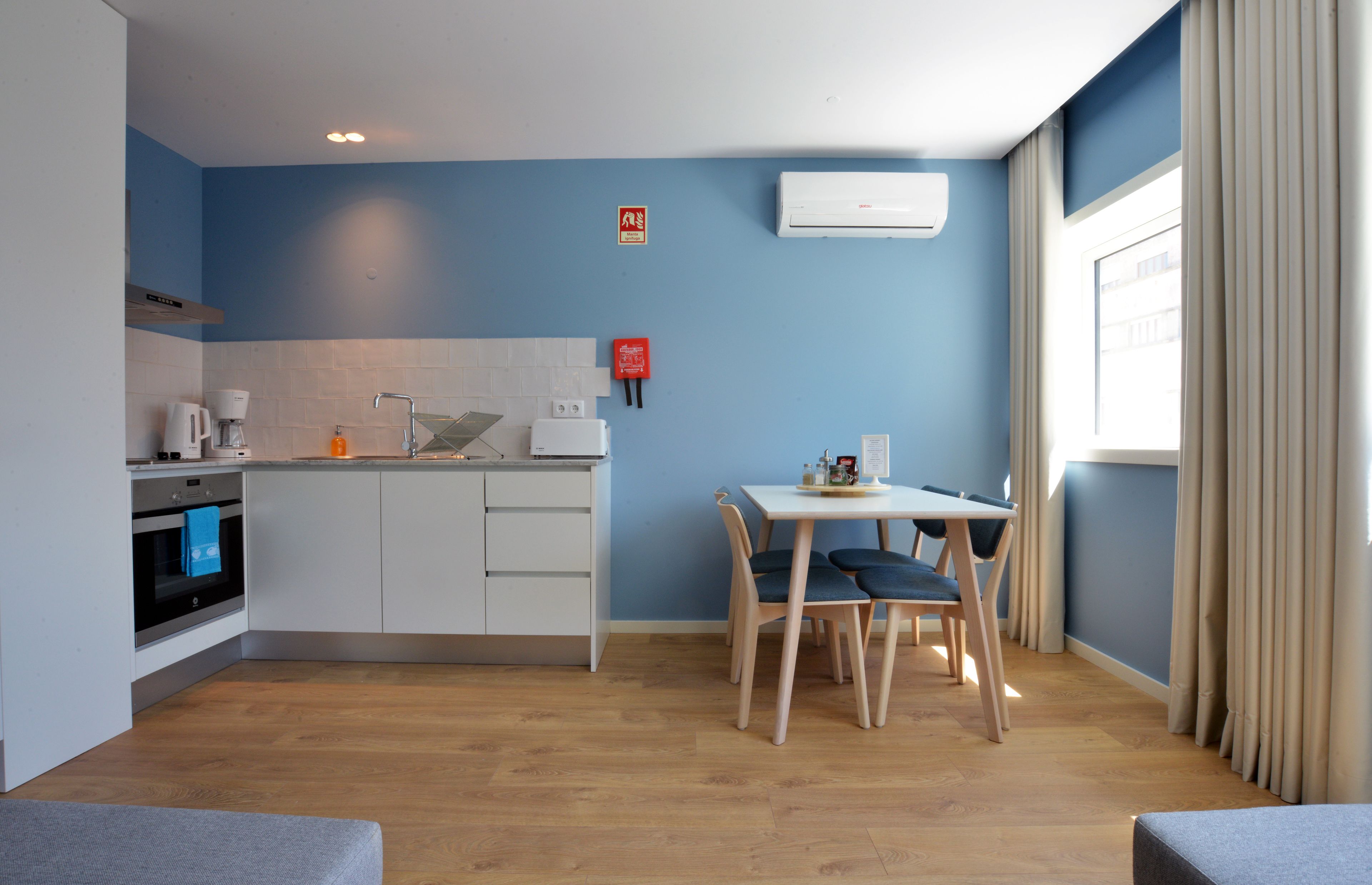 Une cuisine compacte avec des meubles blancs, une machine à café et une petite table à manger avec des chaises.