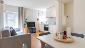 A modern living room with a sofa, dining table, and kitchen area.