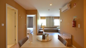 A hotel room with a dining area, a sofa, a small table with a tray, and a fire extinguisher on the wall.