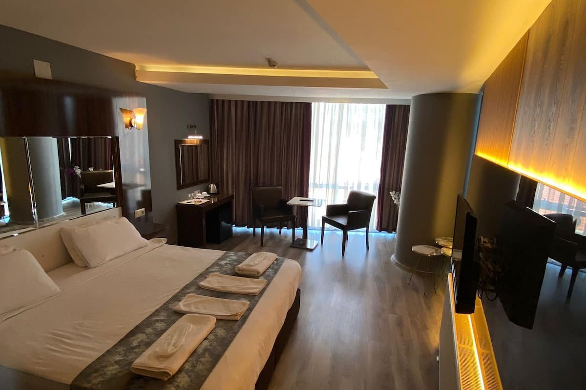 A hotel room with a large bed, a desk, a chair, and a television.