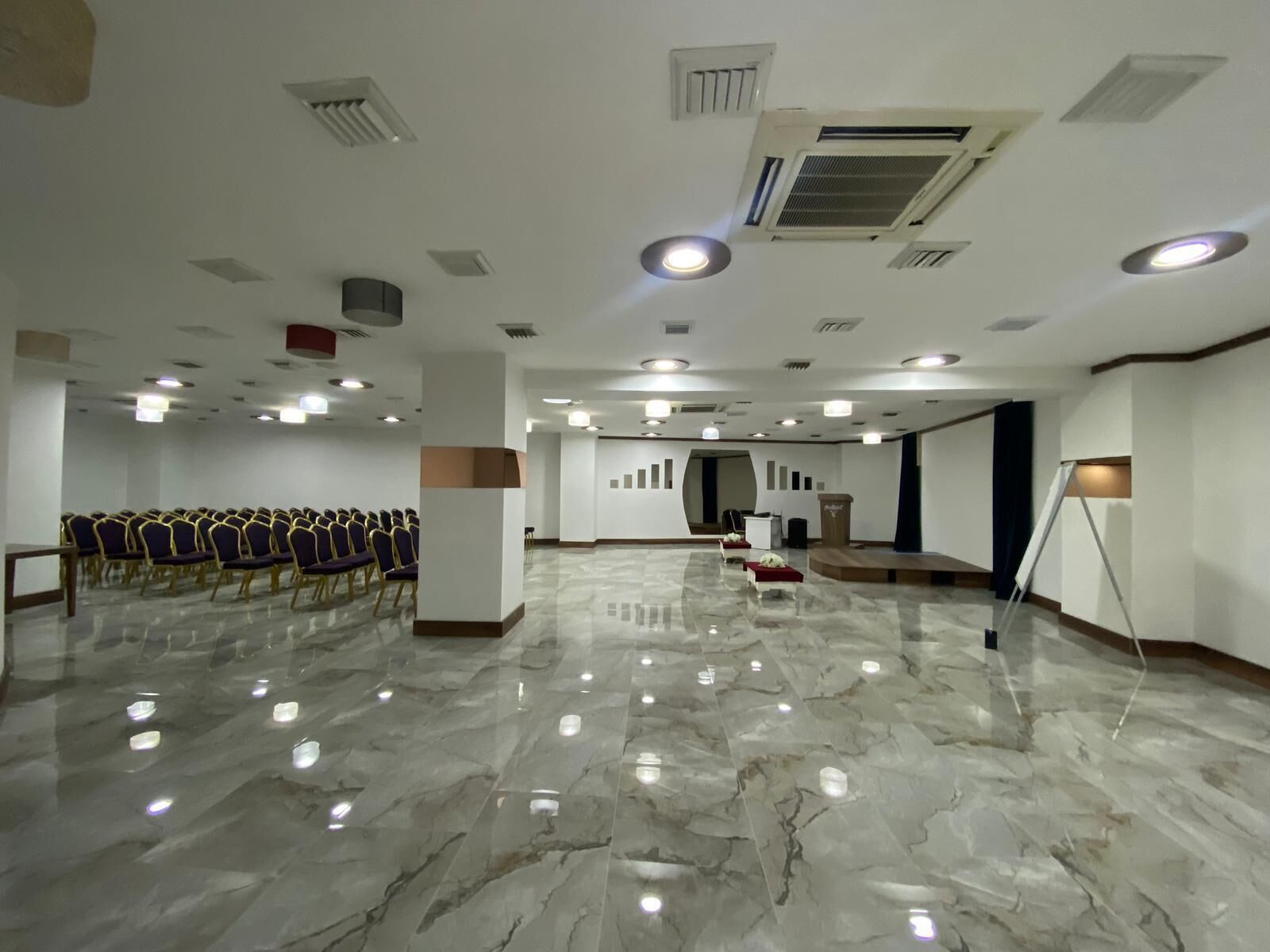 A spacious hall with rows of chairs, a podium, and a stage.
