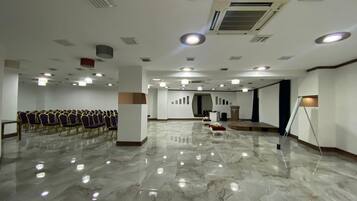 A spacious hall with rows of chairs, a podium, and a stage.