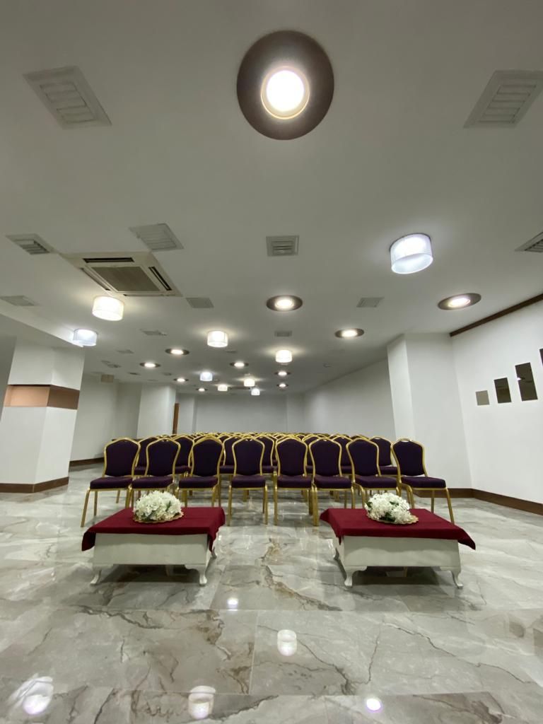 A conference room with rows of purple chairs, a marble floor, and ceiling lights.