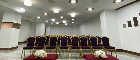 A conference room with rows of purple chairs, a marble floor, and ceiling lights.
