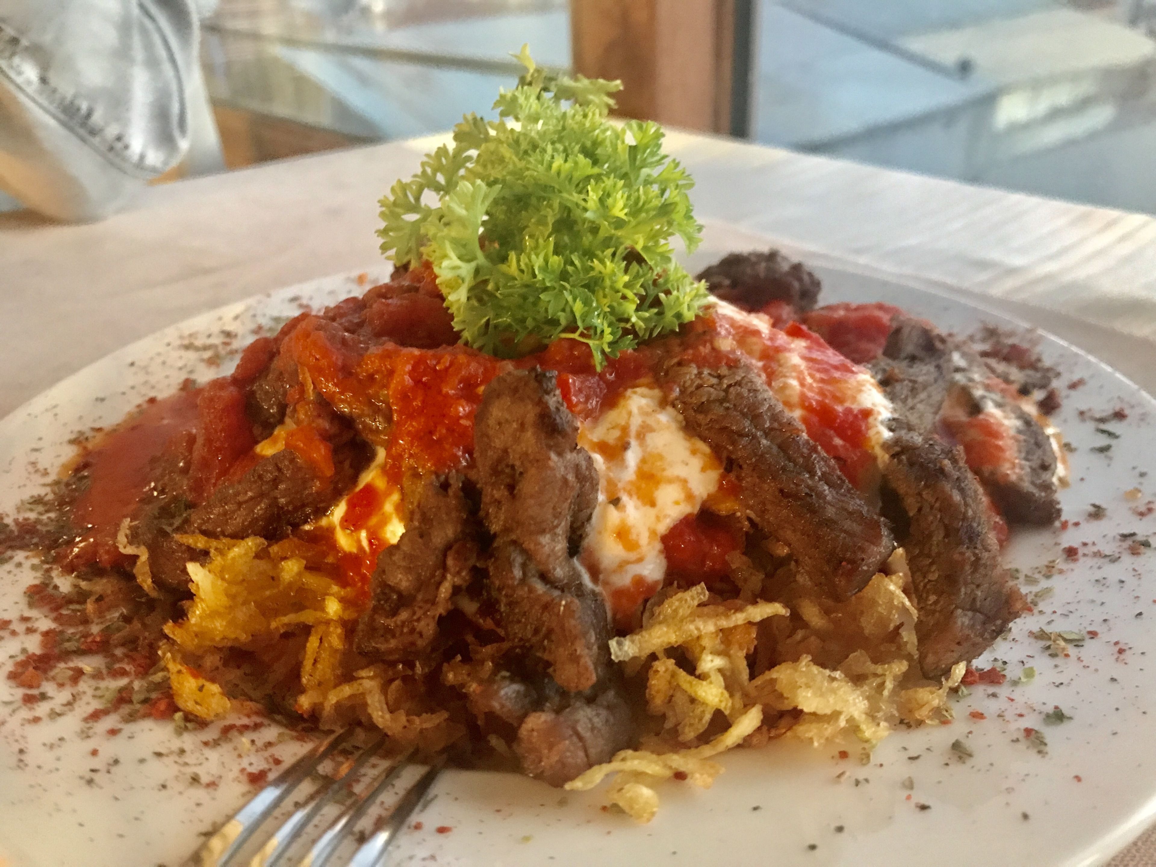 A plate of food with meat, sauce, and garnish.