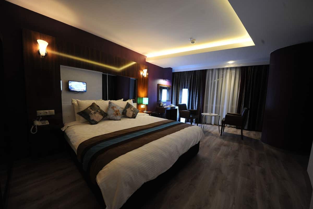 A modern hotel room with a large bed, bedside tables, a desk, and a chair.