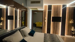 A modern hotel room with a large bed, a mirror, and a view of a yellow chair in the background. - Usak Yucel Hotel (Usak)